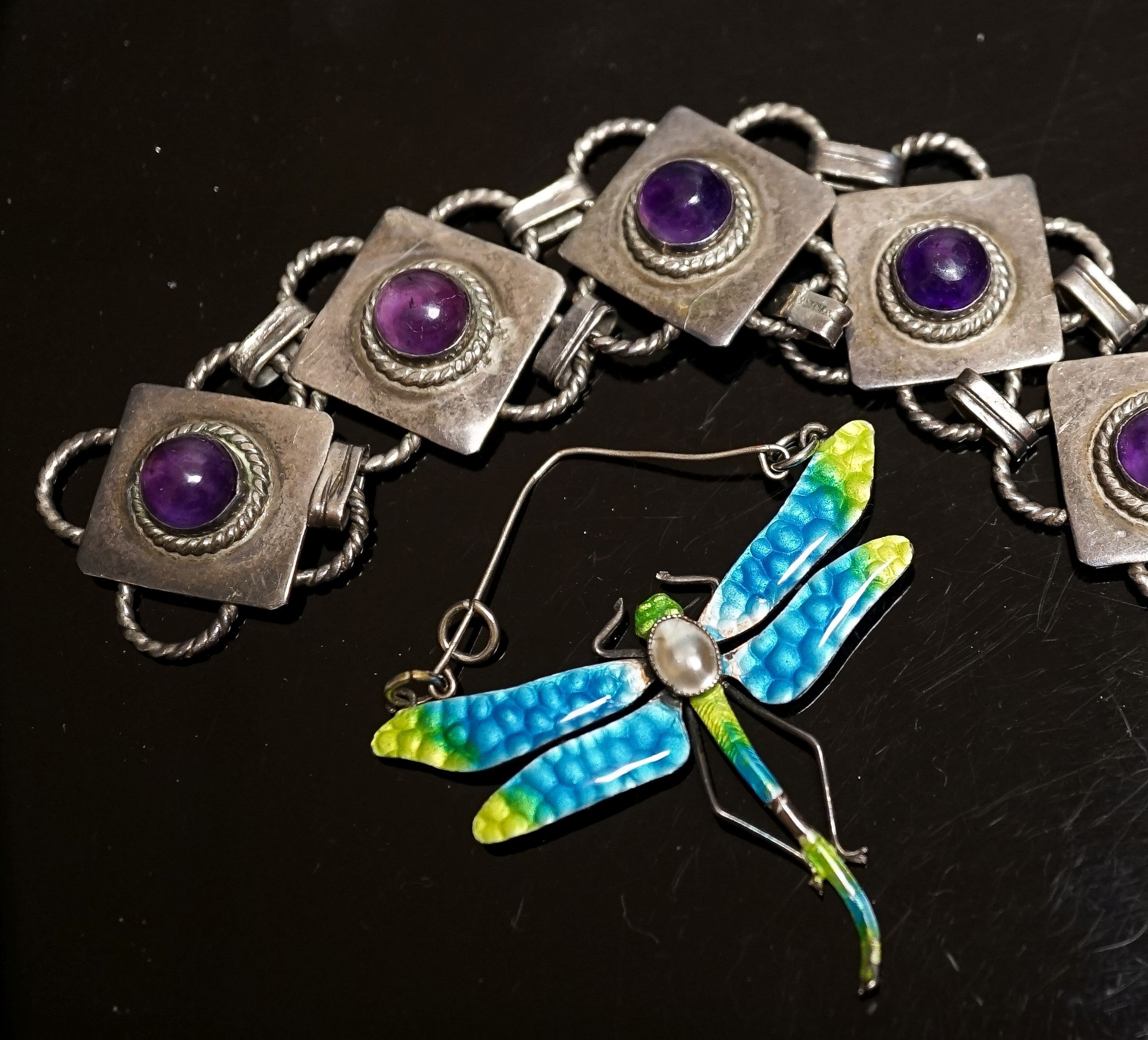 A white metal and seven stone cabochon amethyst set bracelet, 18.5cm and a white metal, mother of pear, and enamel set dragonfly pendant(a.f.), diameter 47mm.